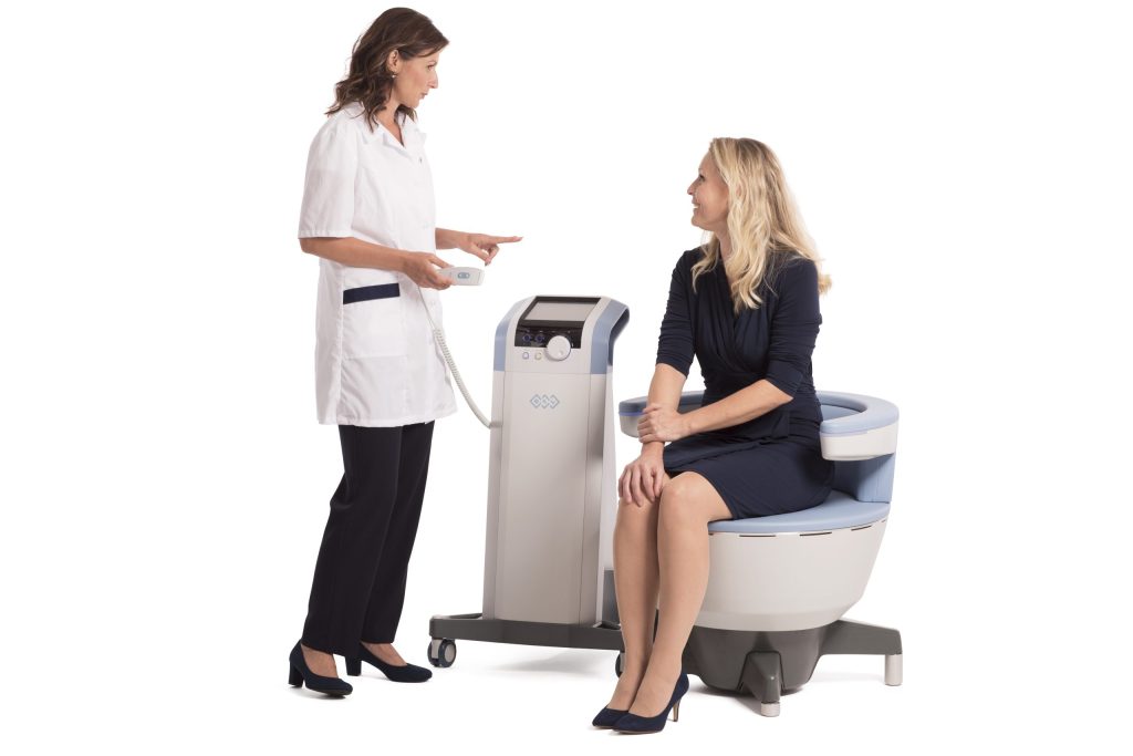 Model sitting in chair talking to provider next to emsella machine