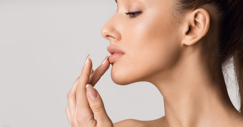 Side profile of woman touching her full lips (model)