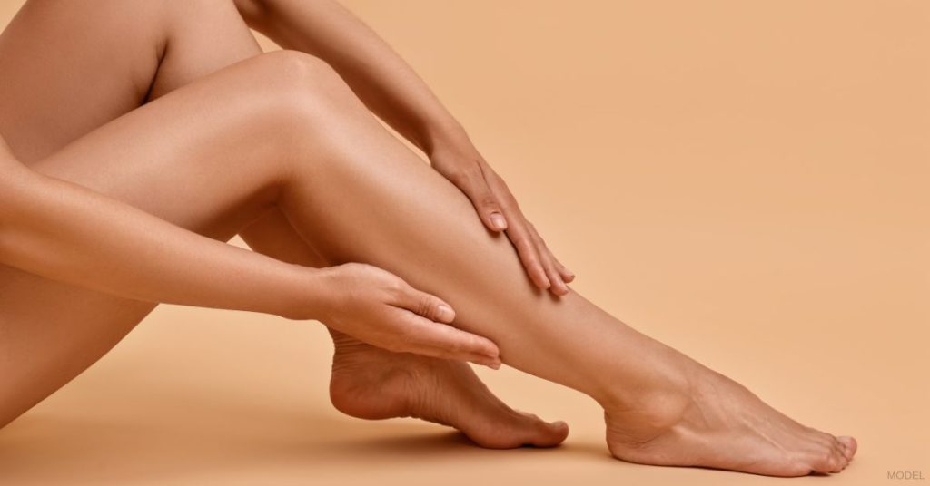 A model's hand touching their smooth legs.